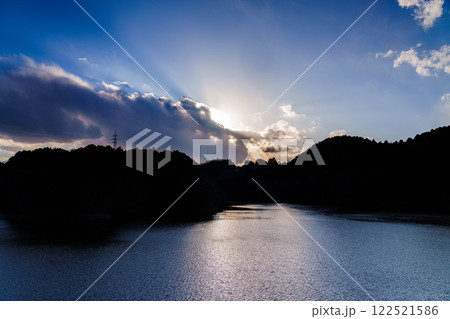奈良市東部大和高原にある奈良市の水瓶布目ダム　真冬の風景　雲に隠され湖面に淡い光を投げかける太陽 122521586