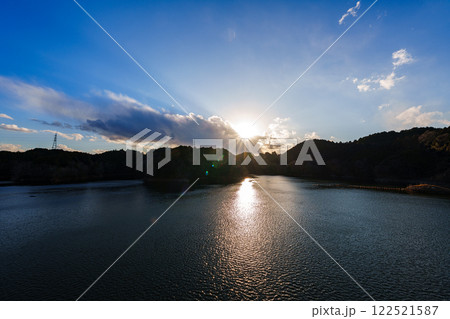 奈良市東部大和高原にある奈良市の水瓶布目ダム　真冬の風景　雲間から顔を覗かせる夕日と湖面の光の道① 122521587