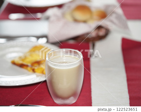 A glass of oat milk on red placemat on table. Breakfast at home. 122523651