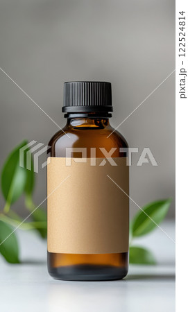 Minimalist brown bottle with blank label and green leaves nearby 122524814