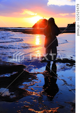 夕日が沈む海岸で日に向かってい祈りを捧げる人　和歌山県田辺市の海岸で撮影する夕日とリフレクション 122525479