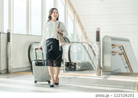 駅でエスカレーターに乗るスーツケースを持った出張・旅行帰りの女性・ビジネスウーマン 122526201