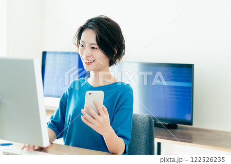 オフィスでスマホを操作する若い女性 オフィスでスマホを操作する若い女性 122526235