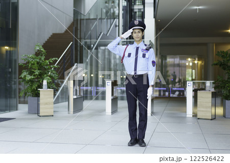 オフィスビルのエントランスロビーに立って敬礼する若い警備員　撮影協力:スカパー東京メディアセンター 122526422
