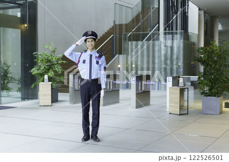 オフィスビルのエントランスロビーに立って敬礼する若い警備員　撮影協力:スカパー東京メディアセンター 122526501