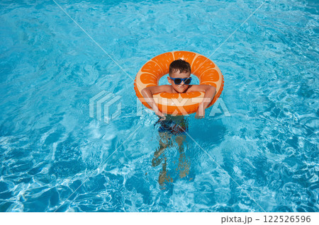 child boy in an inflatable circle learns to swim in swimming pool at hotel on summer vacation child boy in an inflatable circle learns to swim in swimming pool at hotel on summer vacation 122526596