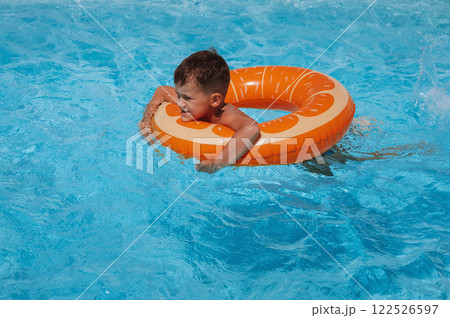 small child boy in an inflatable circle learns to swim in the swimming pool at hotel on summer vacation 122526597