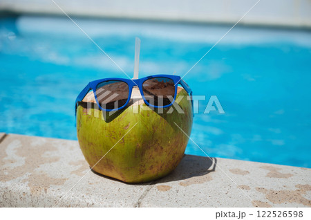 drinking coconut with a straw in sunglasses relax by the swimming pool at resort in the hotel in summer drinking coconut with a straw in sunglasses relax by the swimming pool at resort in the hotel in summer 122526598