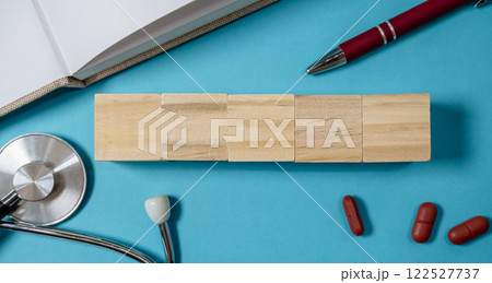 Stack of wooden blocks sits on a blue surface next to a pen and a stethoscope Stack of wooden blocks sits on a blue surface next to a pen and a stethoscope 122527737