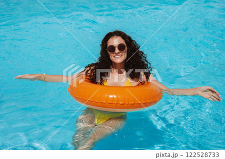 young beautiful happy girl in sunglasses relax in an inflatable circle in pool at a hotel on vacation at resort in the summer holidays young beautiful happy girl in sunglasses relax in an inflatable circle in pool at a hotel on vacation at resort in the summer holidays 122528733