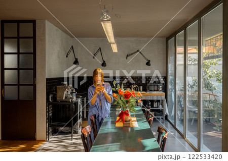 Woman Using Smartphone in a Stylish Modern Kitchen 122533420