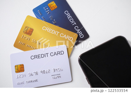 Pile of credit cards with smartphone on white background. Cashless technology and credit card payment concept. Pile of credit cards with smartphone on white background. Cashless technology and credit card payment concept. 122533554