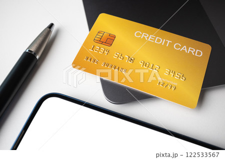 Credit card placed on laptop with pen and smartphone on white background. Cashless technology and credit card payment concept. 122533567