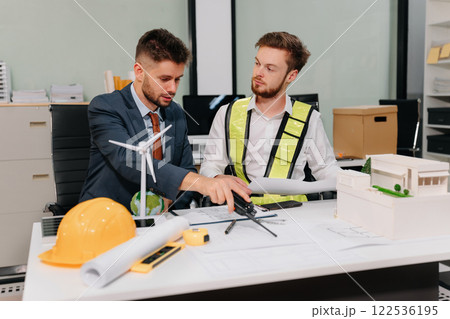 Engineer Teamwork Meeting, Drawing working on blueprint meeting for project working with partner on model building at company office. Engineer Teamwork Meeting, Drawing working on blueprint meeting for project working with partner on model building at company office. 122536195