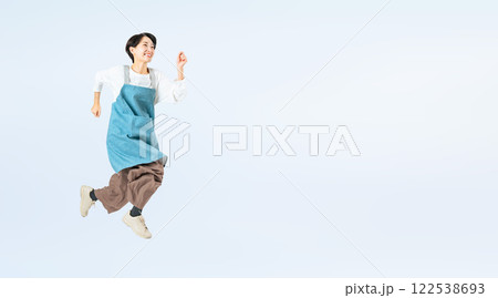 ジャンプするエプロンをつけたミドル女性の全身写真 122538693