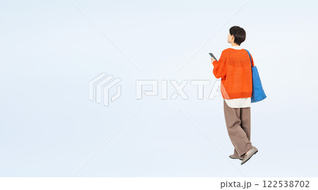 スマホを持って歩くおしゃれなミドル女性の後ろ姿の全身写真 スマホを持って歩くおしゃれなミドル女性の後ろ姿の全身写真 122538702