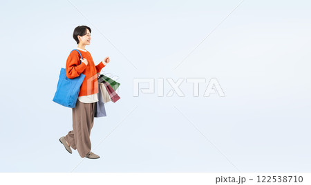 ショッピングバッグを持って歩くおしゃれなミドル女性の全身写真 122538710