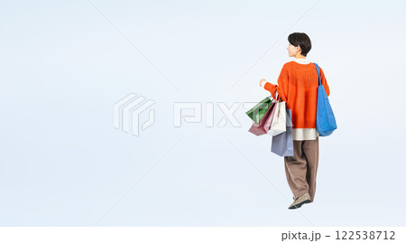 ショッピングバッグを持って歩くおしゃれなミドル女性の後ろ姿の全身写真 122538712