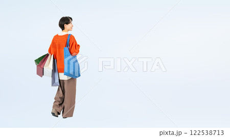 ショッピングバッグを持って歩くおしゃれなミドル女性の後ろ姿の全身写真 122538713