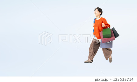 ショッピングバッグを持ってジャンプするおしゃれなミドル女性の全身写真 122538714