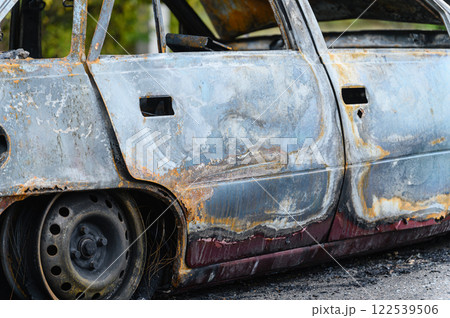Burned car wreck abandoned on roadside in nature 122539506