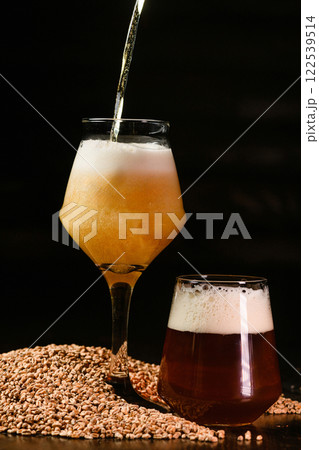 Dark and light beer glasses with pouring beer on dark background Dark and light beer glasses with pouring beer on dark background 122539514