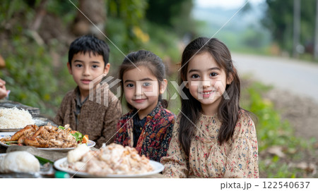 Children enjoying meal outdoors with joyful expression, surrounded by nature 122540637