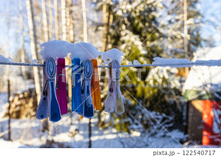 snow-covered clothespins on clothesline close-up 122540717