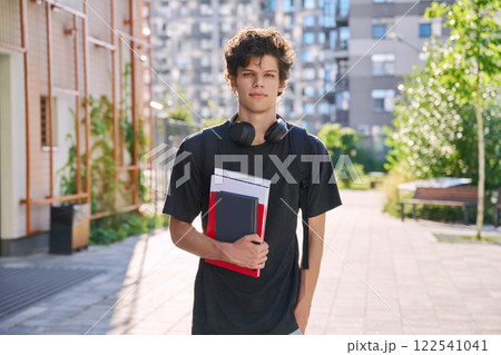 Portrait young male college student with backpack textbooks copybooks, outdoor 122541041
