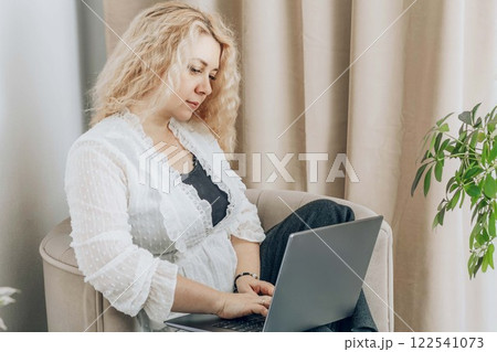 professional woman typing on laptop, home workspace with warm tones and natural elements, concept of freelancing, entrepreneurship, online business 122541073
