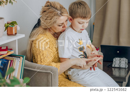 mother teaching young boy at home, both focused on hands, concept of early education, parenting, home schooling mother teaching young boy at home, both focused on hands, concept of early education, parenting, home schooling 122541082
