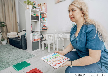 therapist in a blue uniform in bright modern classroom with learning materials and colorful puzzle board, concept of childhood education, speech therapy, cognitive development therapist in a blue uniform in bright modern classroom with learning materials and colorful puzzle board, concept of childhood education, speech therapy, cognitive development 122541117