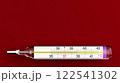Glass mercury thermometer for measuring human body temperature. Red background. Medicine and health 122541302