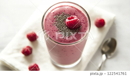 Berry smoothie topped with a sprinkle of chia seeds and a couple of fresh berries in a tall glass on white background.  122541761