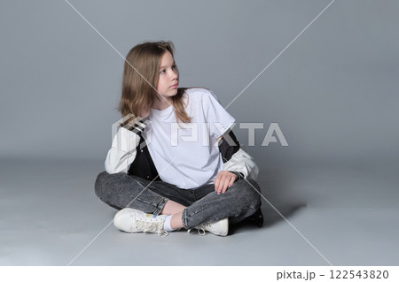 A young girl sits cross-legged on the floor, gazing thoughtfully to the side. This image captures a serene moment, reflecting the introspective nature and calm confidence of youth. A young girl sits cross-legged on the floor, gazing thoughtfully to the side. This image captures a serene moment, reflecting the introspective nature and calm confidence of youth. 122543820