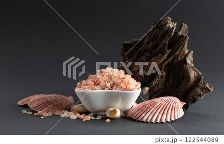 Pink himalayan salt with snags and seashells on a black background. Pink himalayan salt with snags and seashells on a black background. 122544089