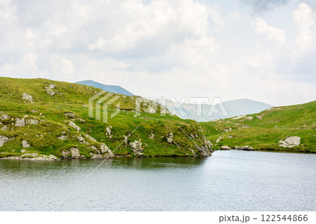 alpine lake capra in summer. tourism attraction. cloudy weather. scenery of fagaras ridge. carpathian mountain range. romania landscape. natural glacial with rocky shore alpine lake capra in summer. tourism attraction. cloudy weather. scenery of fagaras ridge. carpathian mountain range. romania landscape. natural glacial with rocky shore 122544866