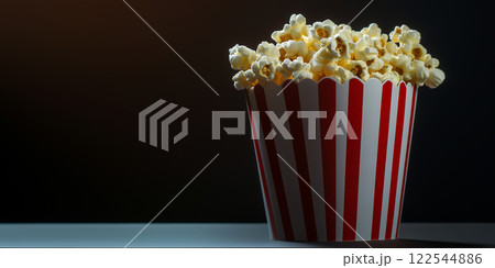 Popcorn bucket. Red and white stripes. Movie night snack food. Dramatic lighting close-up photography black background Popcorn bucket. Red and white stripes. Movie night snack food. Dramatic lighting close-up photography black background 122544886
