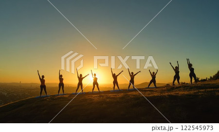 Silhouettes of people practicing yoga at sunset. 122545973