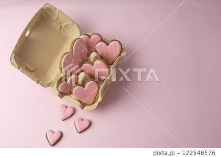 ginger cookies in the shape of hearts with pink frosting in an egg carton, creative baking concept for Valentine's Day 122546576