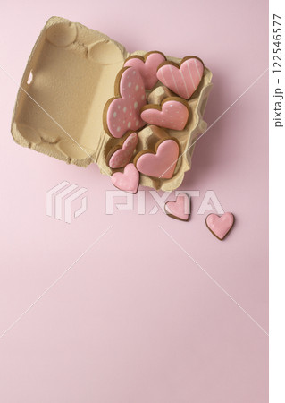 heart-shaped cookies with pink icing in an egg carton, vertical, creative baking concept for Valentine's Day heart-shaped cookies with pink icing in an egg carton, vertical, creative baking concept for Valentine's Day 122546577