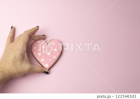 female hand holding cookies in the shape of hearts with pink icing, creative baking concept for Valentine's Day female hand holding cookies in the shape of hearts with pink icing, creative baking concept for Valentine's Day 122546581