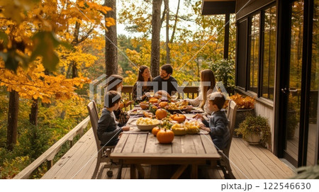 Family Thanksgiving dinner on a deck overlooking autumn foliage. 122546630