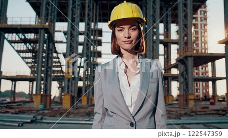 Confident female architect posing on construction site 122547359