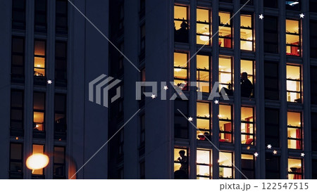 Night falling on apartment building, silhouettes of people in windows 122547515