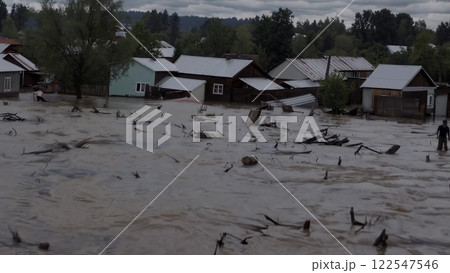 Flood devastating a village, carrying debris and damaging houses 122547546