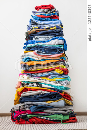 A very tall stack of folded colored clothes for charity, washing, ironing and sorting. 122548398