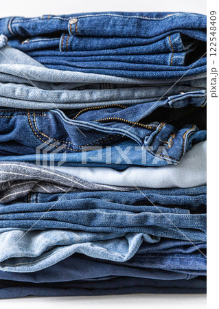 Stack of various shades of blue jeans on white background Stack of various shades of blue jeans on white background 122548409