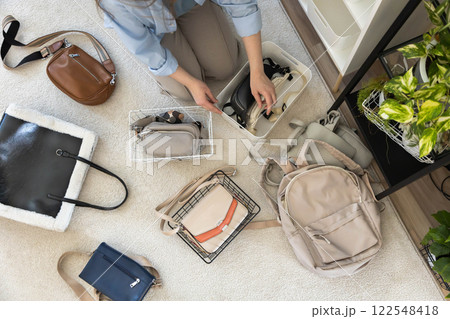 A young woman puts various women's handbags for storage in her home wardrobe. Accessories and bags. A young woman puts various women's handbags for storage in her home wardrobe. Accessories and bags. 122548418