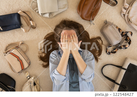 A young woman puts various women's handbags for storage in her home wardrobe. Accessories and bags. A young woman puts various women's handbags for storage in her home wardrobe. Accessories and bags. 122548427